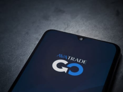 Lod, Israel - July 16,2023: Avatrade app launch screen on smartphone on dark marble stone background. Top view flat lay with copy space.