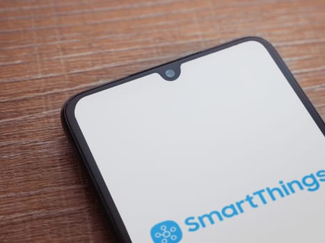 Lod, Israel - July 16,2023: Smartthings app launch screen on smartphone on wooden background. Top view flat lay with copy space.