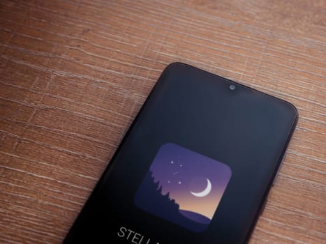 Lod, Israel - July 16,2023: Stellarium - Star Map app launch screen on smartphone on wooden background. Top view flat lay with copy space.