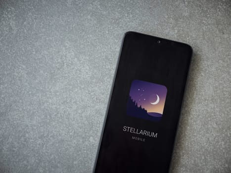 Lod, Israel - July 16,2023: Stellarium - Star Map app launch screen on smartphone on ceramic stone background. Top view flat lay with copy space.