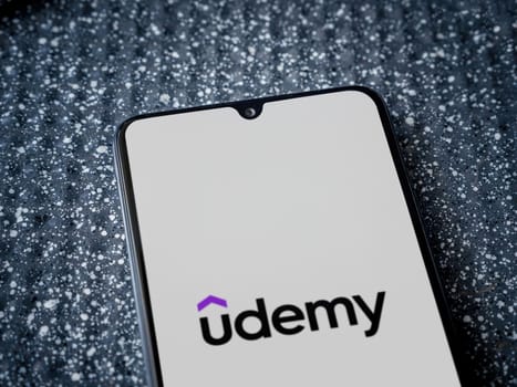 Lod, Israel - July 16,2023: Udemy app launch screen on the display of a black mobile smartphone on a metallic background. Close up top view flat lay.