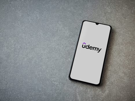 Lod, Israel - July 16,2023: Udemy app launch screen on smartphone on ceramic stone background. Top view flat lay with copy space.