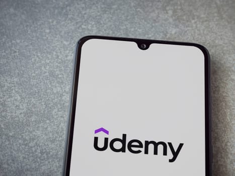 Lod, Israel - July 16,2023: Udemy app launch screen on smartphone on ceramic stone background. Top view flat lay with copy space.
