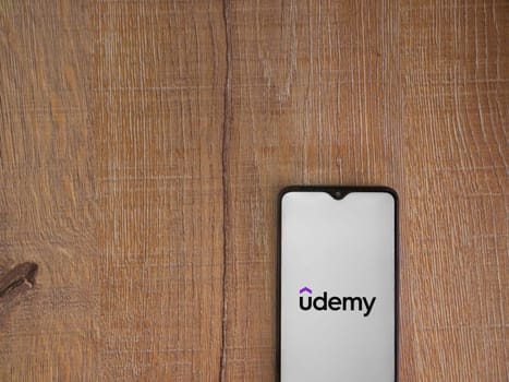 Lod, Israel - July 16,2023: Udemy app launch screen on smartphone on wooden background. Top view flat lay with copy space.