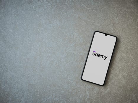 Lod, Israel - July 16,2023: Udemy app launch screen on smartphone on ceramic stone background. Top view flat lay with copy space.