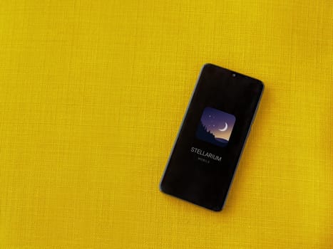 Lod, Israel - July 16,2023: Stellarium - Star Map app launch screen on smartphone on yellow fabric background. Top view flat lay with copy space.