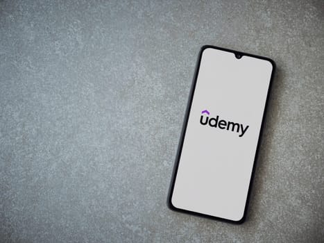 Lod, Israel - July 16,2023: Udemy app launch screen on smartphone on ceramic stone background. Top view flat lay with copy space.