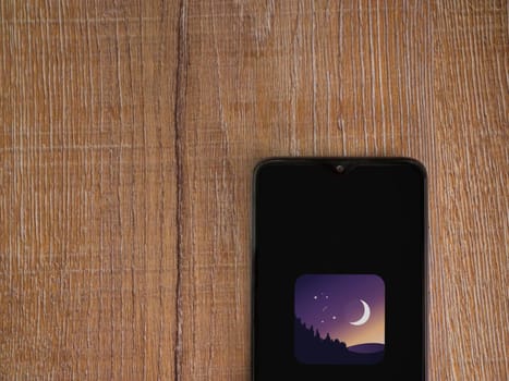 Lod, Israel - July 16,2023: Stellarium - Star Map app launch screen on smartphone on wooden background. Top view flat lay with copy space.