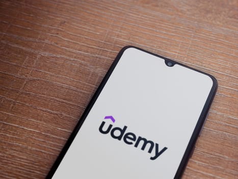 Lod, Israel - July 16,2023: Udemy app launch screen on smartphone on wooden background. Top view flat lay with copy space.