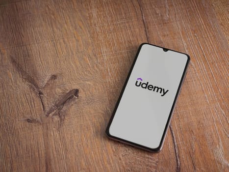 Lod, Israel - July 16,2023: Udemy app launch screen on smartphone on wooden background. Top view flat lay with copy space.