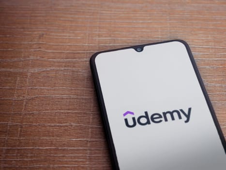 Lod, Israel - July 16,2023: Udemy app launch screen on smartphone on wooden background. Top view flat lay with copy space.