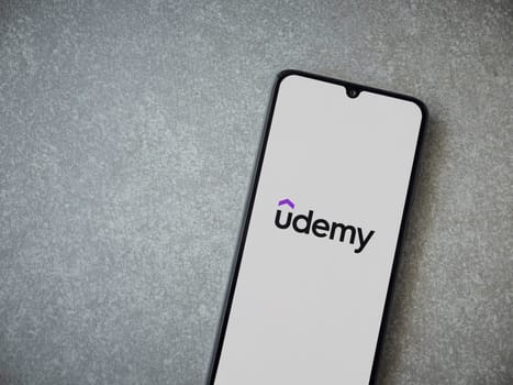 Lod, Israel - July 16,2023: Udemy app launch screen on smartphone on ceramic stone background. Top view flat lay with copy space.