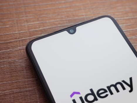 Lod, Israel - July 16,2023: Udemy app launch screen on smartphone on wooden background. Top view flat lay with copy space.