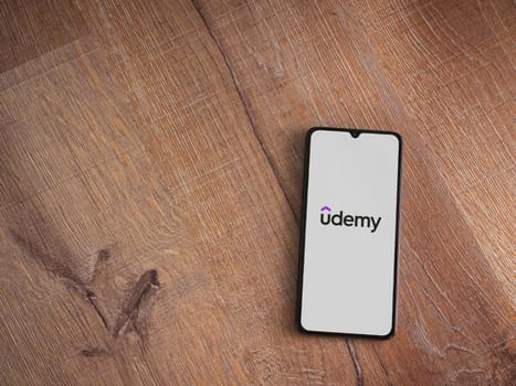Lod, Israel - July 16,2023: Udemy app launch screen on smartphone on wooden background. Top view flat lay with copy space.