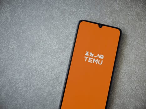 Lod, Israel - July 16,2023: Temu app launch screen on smartphone on ceramic stone background. Top view flat lay with copy space.