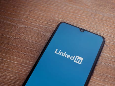 Lod, Israel - July 16,2023: LinkedIn app launch screen on smartphone on wooden background. Top view flat lay with copy space.