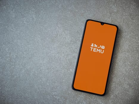 Lod, Israel - July 16,2023: Temu app launch screen on smartphone on ceramic stone background. Top view flat lay with copy space.
