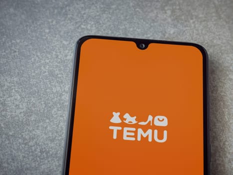 Lod, Israel - July 16,2023: Temu app launch screen on smartphone on ceramic stone background. Top view flat lay with copy space.