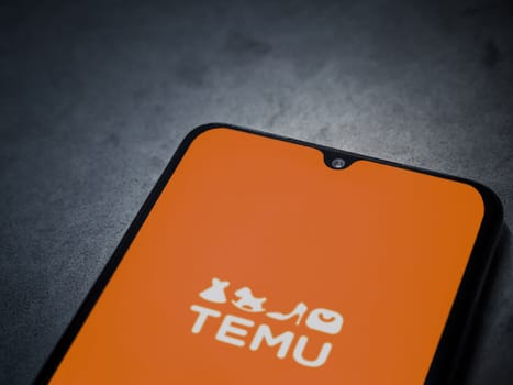 Lod, Israel - July 16,2023: Temu app launch screen on smartphone on dark marble stone background. Top view flat lay with copy space.