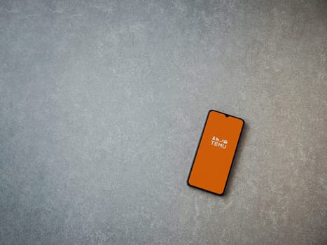 Lod, Israel - July 16,2023: Temu app launch screen on smartphone on ceramic stone background. Top view flat lay with copy space.
