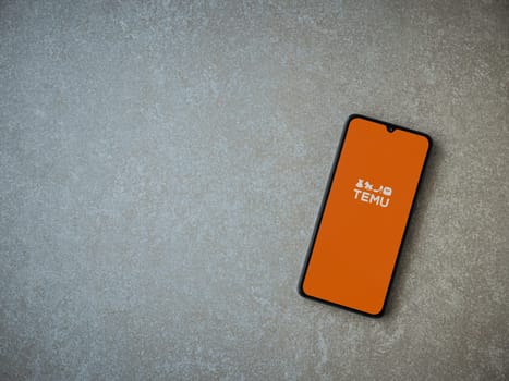 Lod, Israel - July 16,2023: Temu app launch screen on smartphone on ceramic stone background. Top view flat lay with copy space.