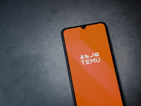 Lod, Israel - July 16,2023: Temu app launch screen on smartphone on dark marble stone background. Top view flat lay with copy space.