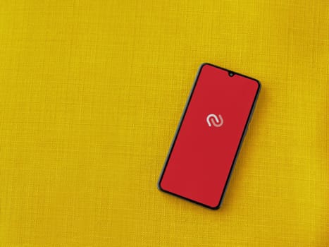 Lod, Israel - July 16,2023: Twilio Authy Authenticator app launch screen on smartphone on yellow fabric background. Top view flat lay with copy space.