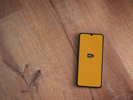Lod, Israel - July 16,2023: USB Camera app launch screen on smartphone on wooden background. Top view flat lay with copy space.