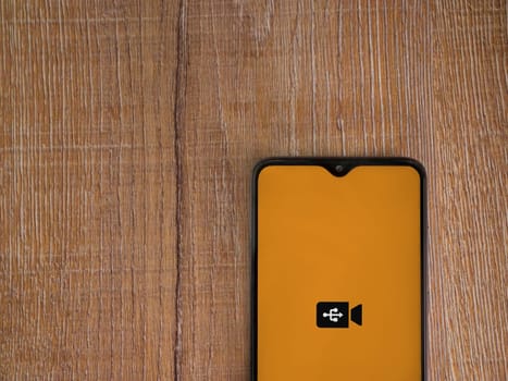 Lod, Israel - July 16,2023: USB Camera app launch screen on smartphone on wooden background. Top view flat lay with copy space.