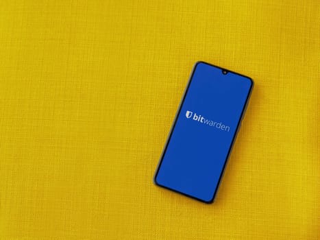 Lod, Israel - July 16,2023: Bitwarden Password Manager app launch screen on smartphone on yellow fabric background. Top view flat lay with copy space.