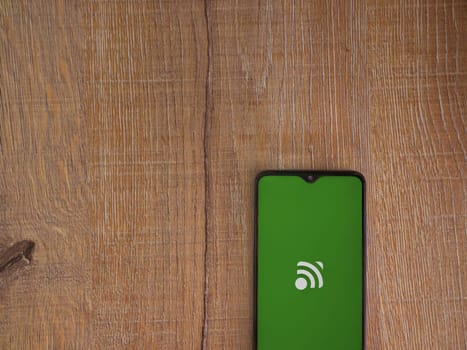 Lod, Israel - July 16,2023: Unified Remote app launch screen on smartphone on wooden background. Top view flat lay with copy space.