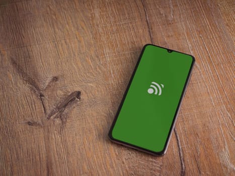 Lod, Israel - July 16,2023: Unified Remote app launch screen on smartphone on wooden background. Top view flat lay with copy space.
