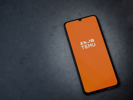 Lod, Israel - July 16,2023: Temu app launch screen on smartphone on dark marble stone background. Top view flat lay with copy space.