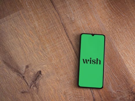 Lod, Israel - July 16,2023: Wish app launch screen on smartphone on wooden background. Top view flat lay with copy space.