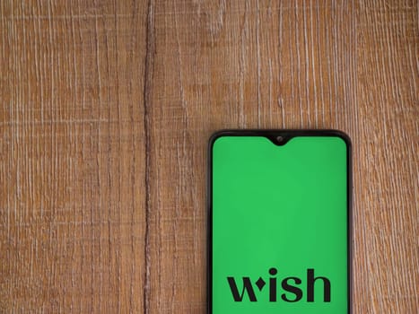 Lod, Israel - July 16,2023: Wish app launch screen on smartphone on wooden background. Top view flat lay with copy space.