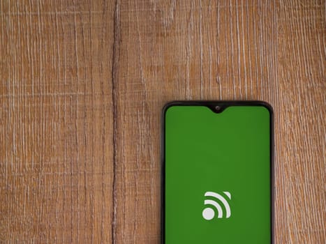 Lod, Israel - July 16,2023: Unified Remote app launch screen on smartphone on wooden background. Top view flat lay with copy space.