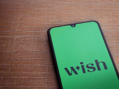 Lod, Israel - July 16,2023: Wish app launch screen on smartphone on wooden background. Top view flat lay with copy space.