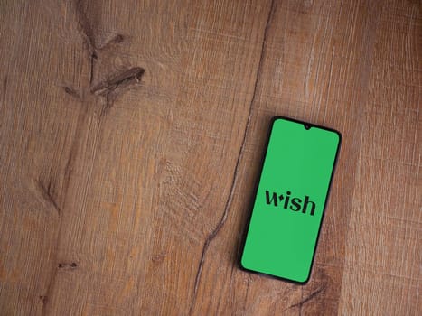 Lod, Israel - July 16,2023: Wish app launch screen on smartphone on wooden background. Top view flat lay with copy space.
