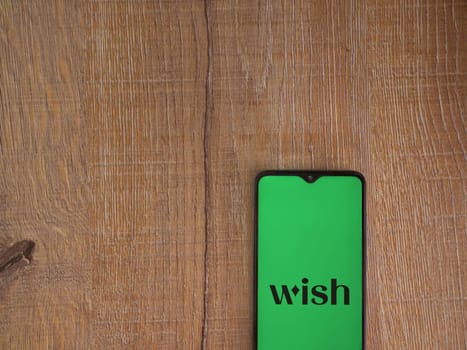 Lod, Israel - July 16,2023: Wish app launch screen on smartphone on wooden background. Top view flat lay with copy space.