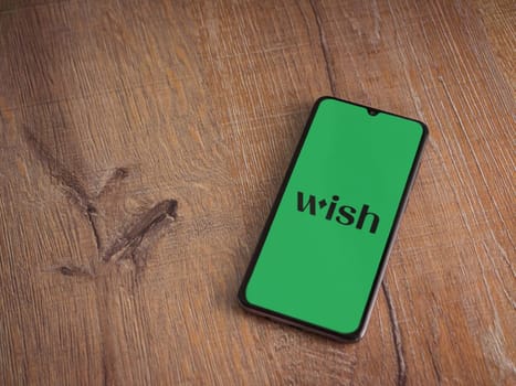 Lod, Israel - July 16,2023: Wish app launch screen on smartphone on wooden background. Top view flat lay with copy space.