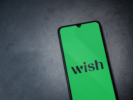 Lod, Israel - July 16,2023: Wish app launch screen on smartphone on dark marble stone background. Top view flat lay with copy space.