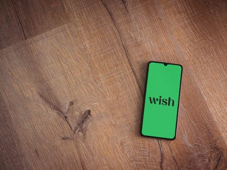 Lod, Israel - July 16,2023: Wish app launch screen on smartphone on wooden background. Top view flat lay with copy space.