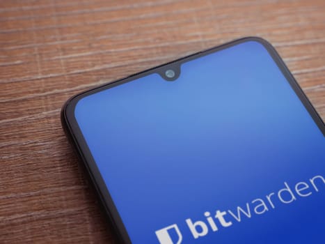 Lod, Israel - July 16,2023: Bitwarden Password Manager app launch screen on smartphone on wooden background. Top view flat lay with copy space.