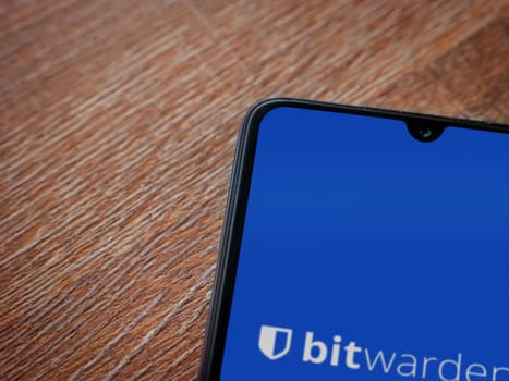 Lod, Israel - July 16,2023: Bitwarden Password Manager app launch screen on smartphone on wooden background. Top view flat lay with copy space.