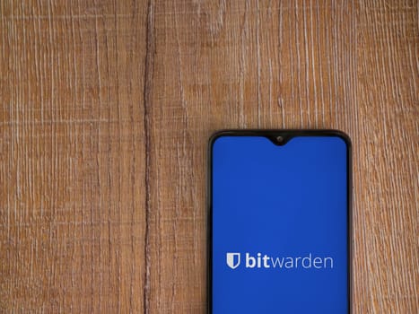 Lod, Israel - July 16,2023: Bitwarden Password Manager app launch screen on smartphone on wooden background. Top view flat lay with copy space.