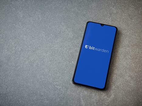 Lod, Israel - July 16,2023: Bitwarden Password Manager app launch screen on smartphone on ceramic stone background. Top view flat lay with copy space.