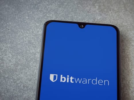 Lod, Israel - July 16,2023: Bitwarden Password Manager app launch screen on smartphone on ceramic stone background. Top view flat lay with copy space.