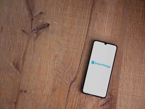 Lod, Israel - July 16,2023: Smartthings app launch screen on smartphone on wooden background. Top view flat lay with copy space.