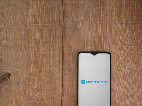 Lod, Israel - July 16,2023: Smartthings app launch screen on smartphone on wooden background. Top view flat lay with copy space.