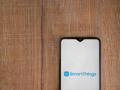 Lod, Israel - July 16,2023: Smartthings app launch screen on smartphone on wooden background. Top view flat lay with copy space.